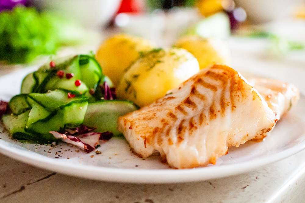 Healthy meal at a senior living community: fish, potatoes, and cucumber salad.